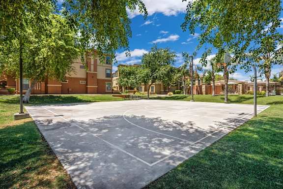 A basketball court is surrounded by grass and trees at Superstition Canyon Apartments, Mesa, Arizona