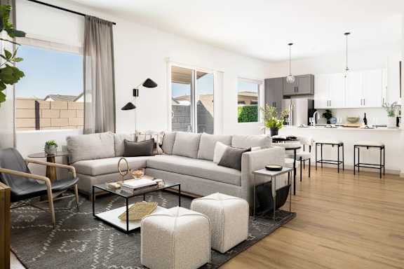 A modern living room with a grey sofa, a glass coffee table, and a black chair. at Villas on Ash Apartments, Gilbert