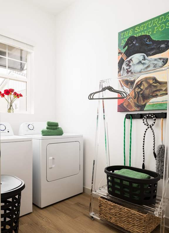 A laundry room with a basket on the floor and a washing machine and dryer in the background. at Villas on Ash Apartments, Gilbert, Arizona