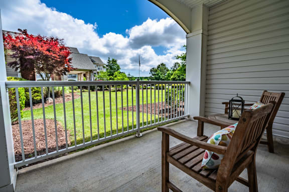 the view from the balcony of a house with a yard and two rocking chairs