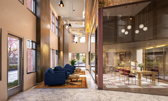 a lobby with blue couches and a table with chairs and a large glass door at Link Apartments® Broad Ave, Memphis, 38112