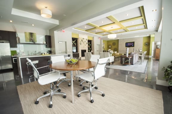 The clubroom with table and chair, smart TV and fire place at Link Apartments® Manchester, Richmond, VA