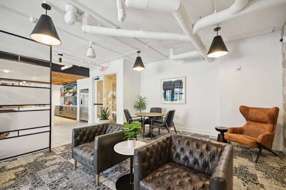 A room with a brown leather couch and a white table. at Link Apartments® 4th Street, Winston-Salem, North Carolina