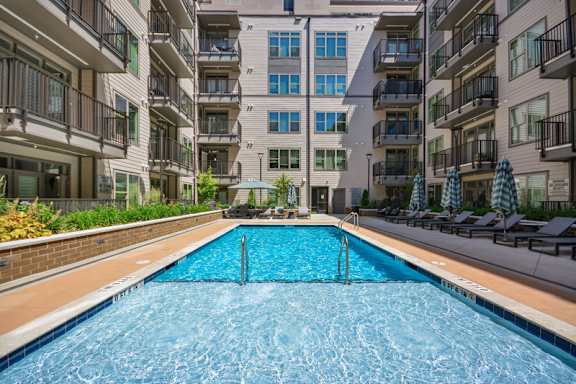 A swimming pool in front of apartment buildings. at Link Apartments® 4th Street, Winston-Salem, North Carolina
