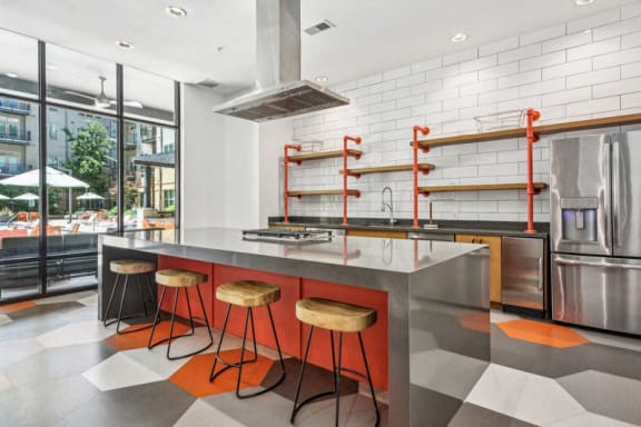the kitchen has a large island with orange stools and stainless steel appliances at Link Apartments Innovation Quarter, North Carolina, 27101