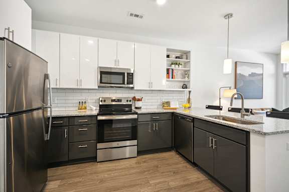 A modern kitchen with black and white appliances and cabinets.