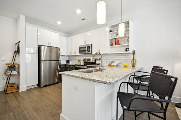 A kitchen with a white counter top and black chairs.