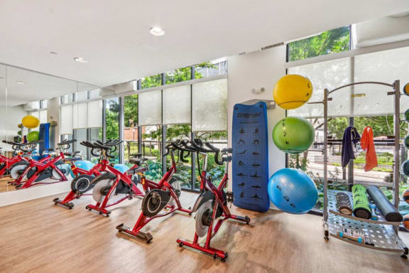 the gym has plenty of exercise equipment and floor to ceiling windows at Link Apartments Innovation Quarter, Winston Salem