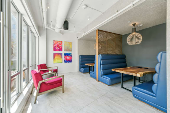 a living room with blue couches and chairs and a wooden table  at Link Apartments® H Street, Washington, 20002
