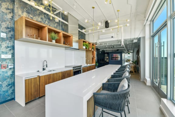 a long kitchen with a long white counter and chairs  at Link Apartments® H Street, Washington