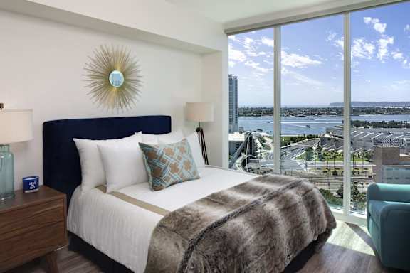 A bedroom with a large bed and a view of the city.