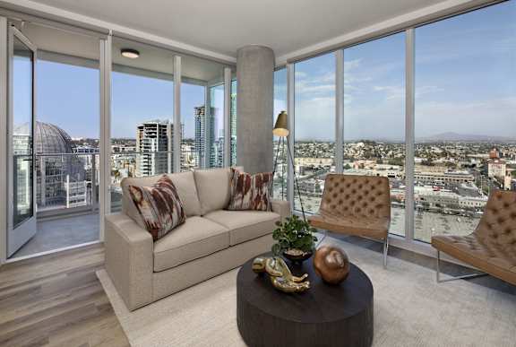 A living room with a view of the cityscape outside the large windows.
