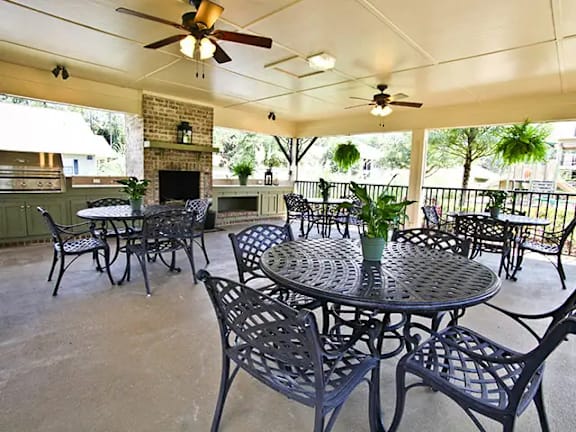 A patio with a table and chairs and a ceiling fan.