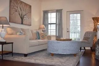 A living room with a white couch and a grey ottoman.