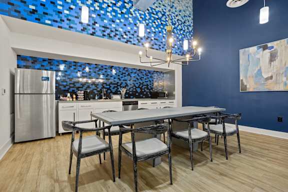 A kitchen with a table and chairs and a blue mosaic tile backsplash.