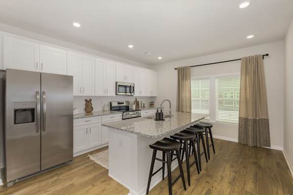 Modern kitchen with island seating and white cabinetry at The Courts at Maverick Yards Apartments, South Carolina, 29662