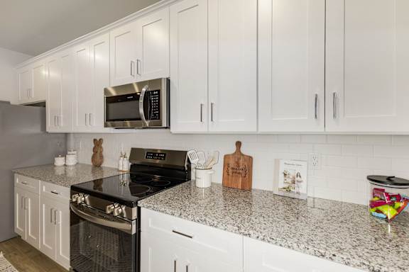 Modern kitchen with white cabinetry and granite countertops at The Courts at Maverick Yards Apartments, Mauldin, 29662