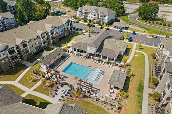 An aerial view of apartment buildings with a pool in the foreground.