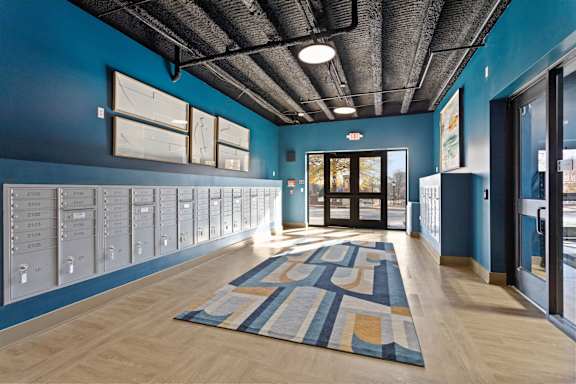 A hallway with a blue wall and a wooden floor with a rug.