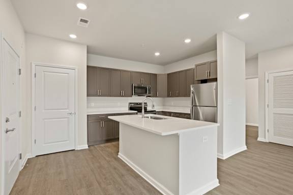 A modern kitchen with a white island and stainless steel appliances.