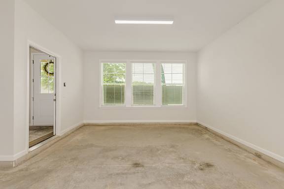 Empty room with three windows and concrete floor at The Courts at Maverick Yards Apartments, Mauldin, 29662