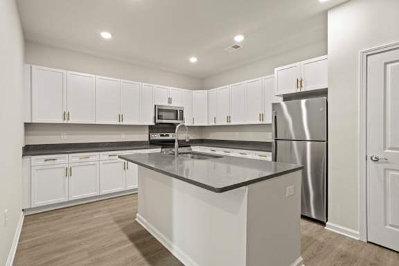 A kitchen with white cabinets and a black countertop.