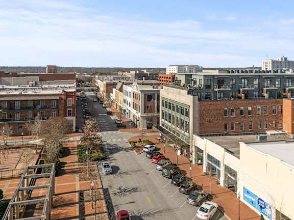 A city street with cars parked on the side and buildings on both sides.