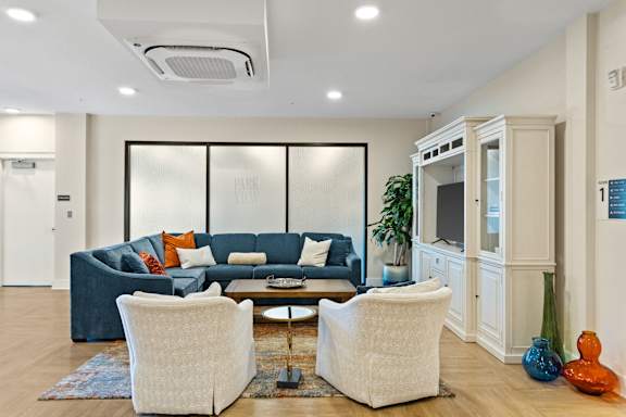 A living room with a blue couch and two white chairs.