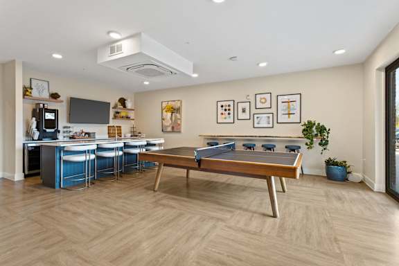 A room with a pool table and a kitchen area.