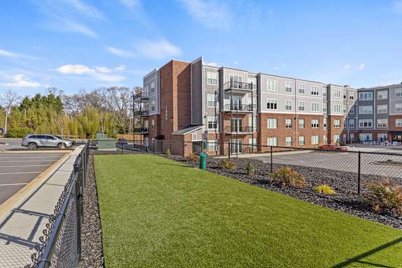 A parking lot is in front of a building with a green lawn.