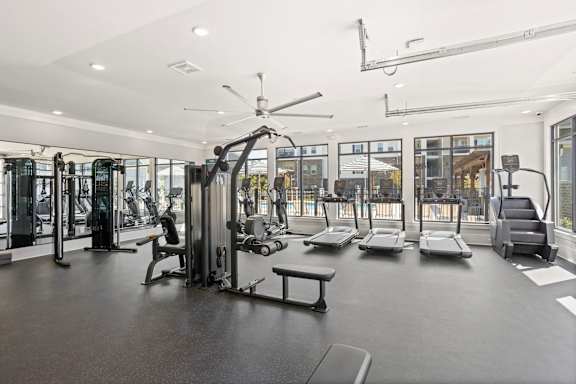 A gym with a variety of equipment including a treadmill, weights, and a bench.