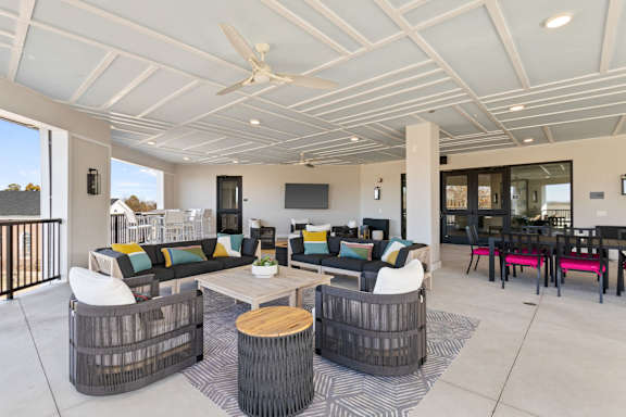 A modern outdoor living space with a white ceiling fan and a black and white striped rug.