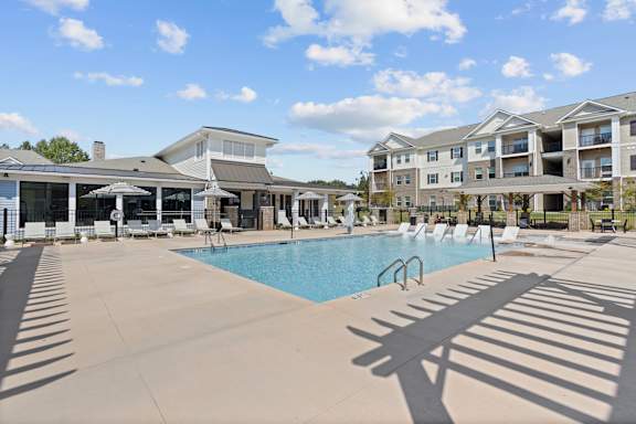 A large swimming pool in front of a building with a sunny day.