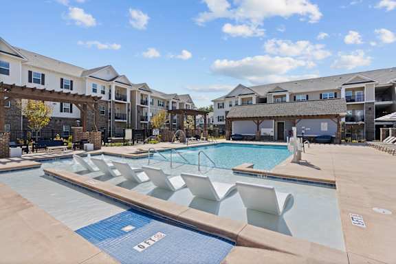 A large swimming pool with lounge chairs and a building in the background.