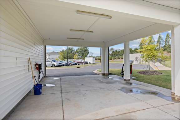 A white covered parking area with a blue bucket on the ground.