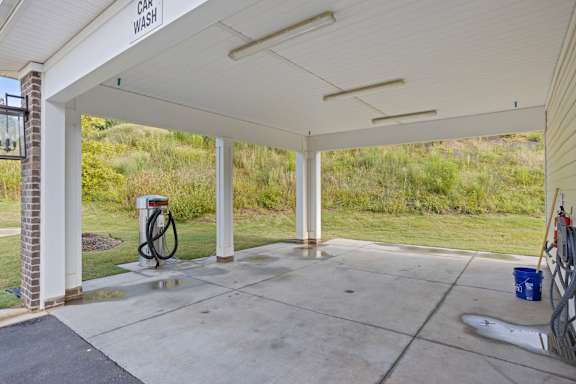 A car wash station with a hose and a sign.