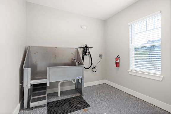A room with a stainless steel sink and a fire extinguisher on the wall.