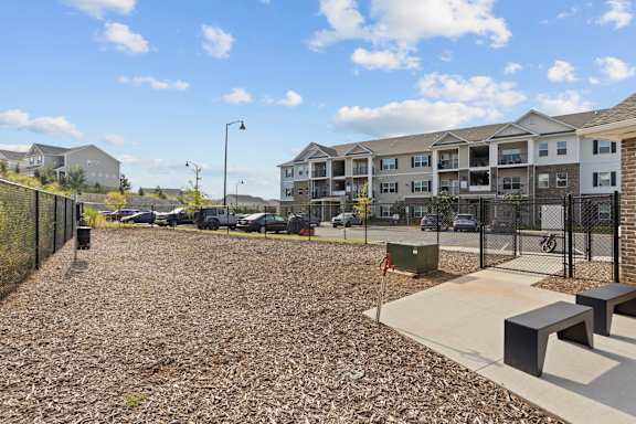 A gravel parking lot with a fence and a bench.