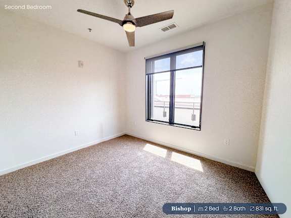 A second bedroom with a ceiling fan and carpeted floor.
