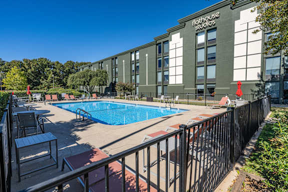 A pool area in front of a building with the words Flat House Studios on it.