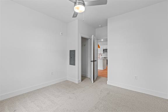 A room with a ceiling fan and a door leading to another room.