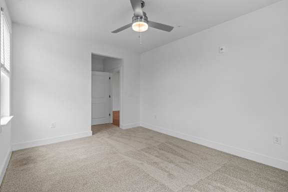 A room with a carpet floor and a ceiling fan.
