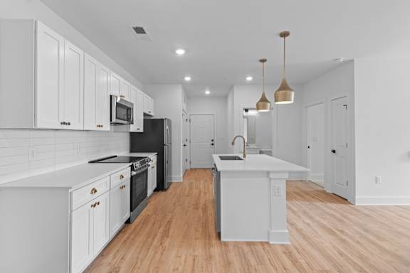 A modern kitchen with white cabinets and a black refrigerator.