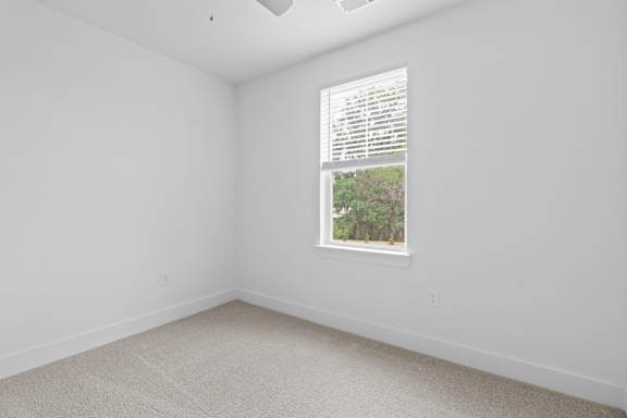 A room with a window showing a view of trees outside.