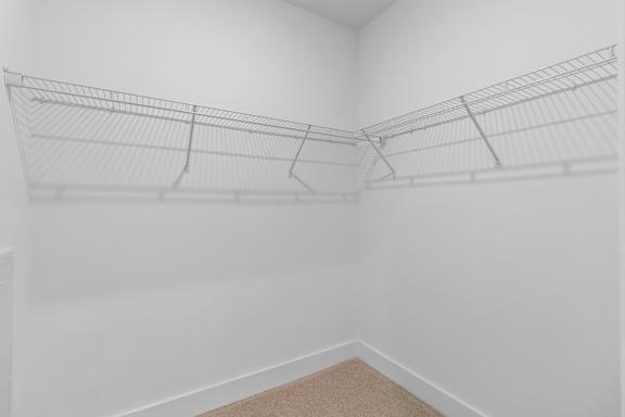 A white room with a carpeted floor and a wire shelving unit.
