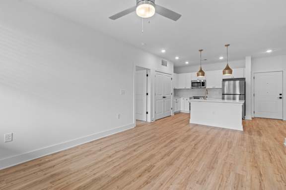 A spacious kitchen and living room with wooden floors and white walls.