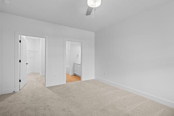A white room with a carpet and a ceiling fan.