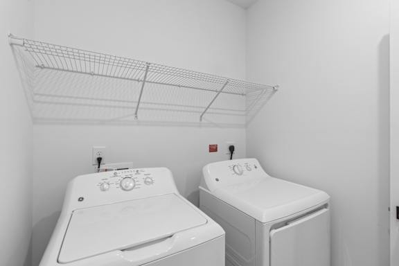 Two white front loading washing machines in a laundry room.