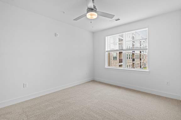A room with a ceiling fan and a window with blinds.