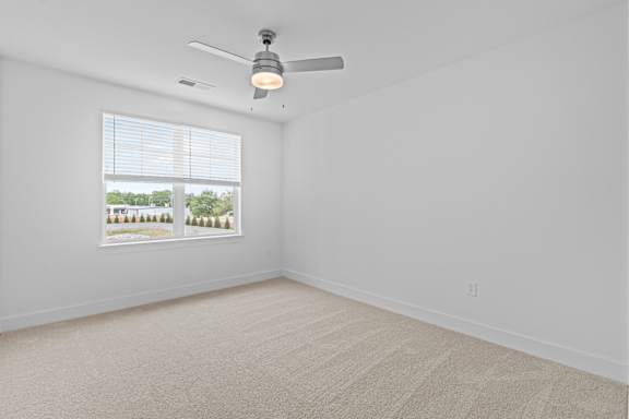 A room with a ceiling fan and a window showing trees outside.